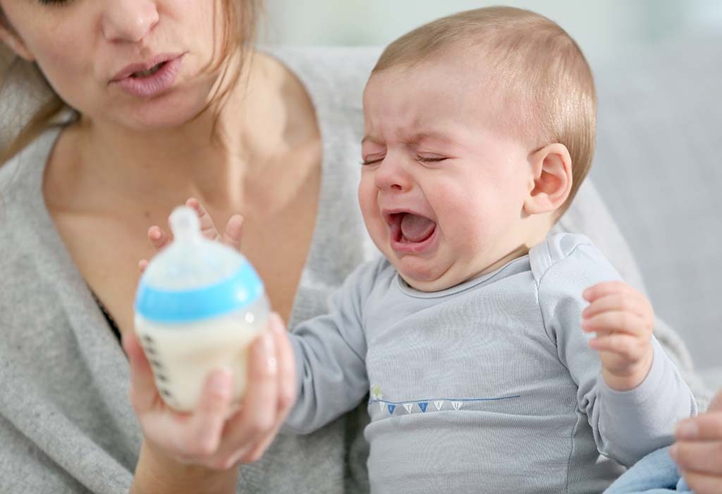 A baby pushing the feeding bottle away