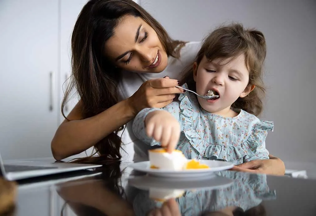 A child touching her food and being fed