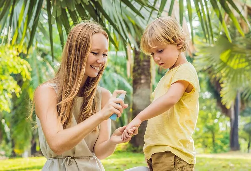 A mother spraying a bug repellent on her child's arms