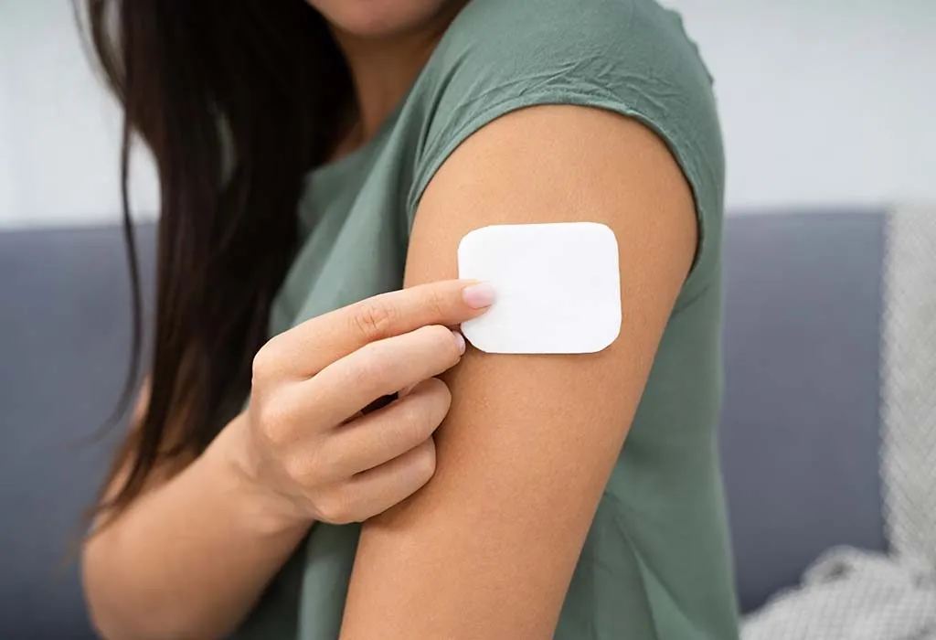 A woman applying contraception patch on her arm