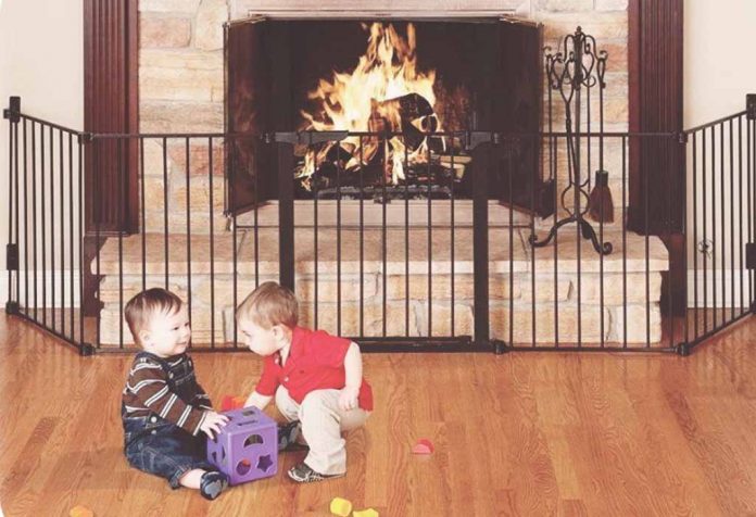 Toddlers playing in front of a baby-proofed fireplace