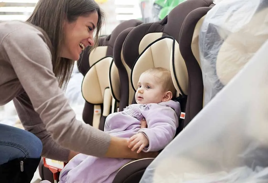 A woman making her baby sit in a car seat
