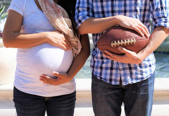 pregnant woman with her husband who's holding a rugby ball